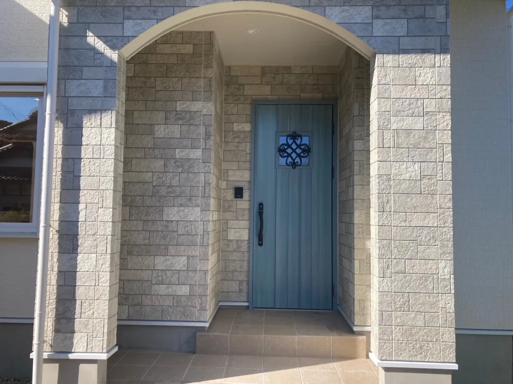 アーチ壁とスタイリッシュな玄関ドアが印象的な、玄関ポーチの写真