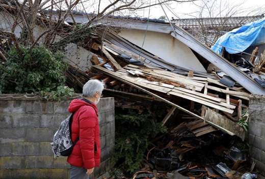 能登地震で崩れた家屋の写真。呆然と見つめる家族。